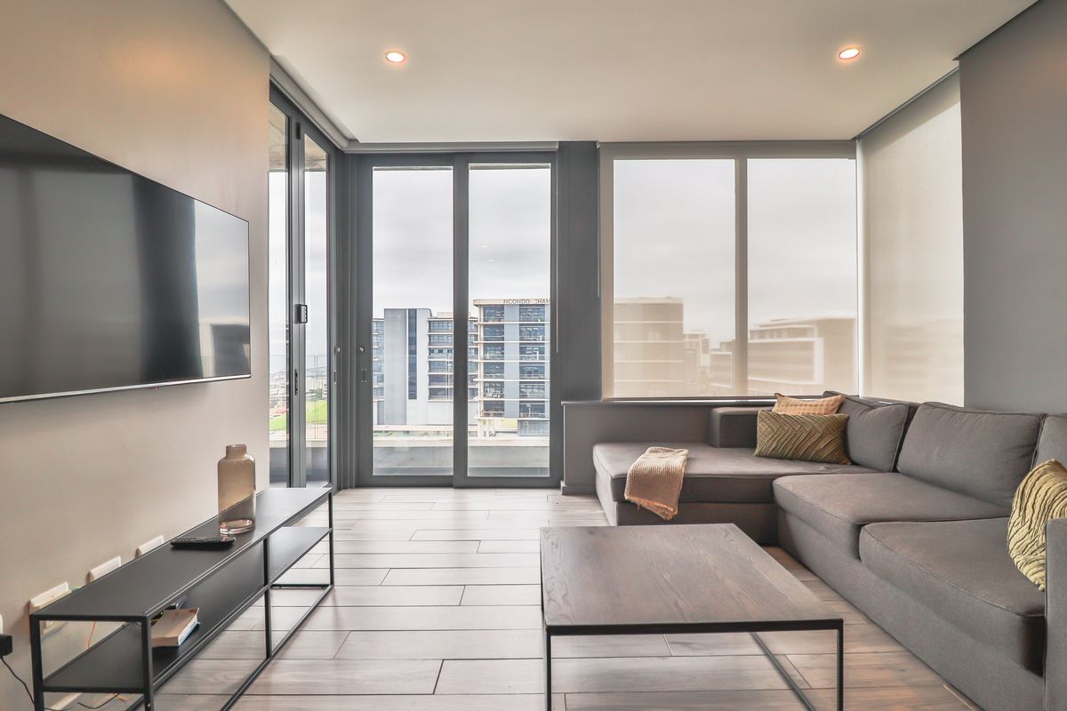 Modern living room featuring large format floor tiles, recessed lighting, and expansive floor-to-ceiling windows with access to a balcony.