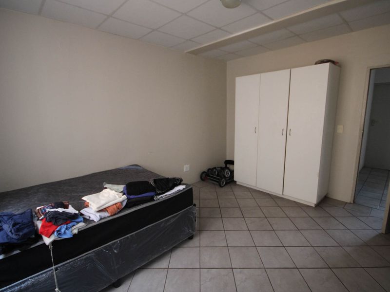 A bedroom featuring tiled flooring, a built-in wardrobe, and a drop ceiling. The space requires cosmetic updates to improve its overall appeal.