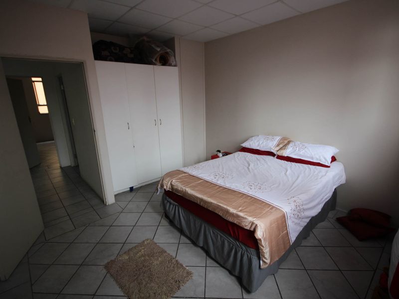 A bedroom featuring built-in cupboards, tiled flooring, and a drop ceiling, requiring some maintenance to the ceiling tiles.
