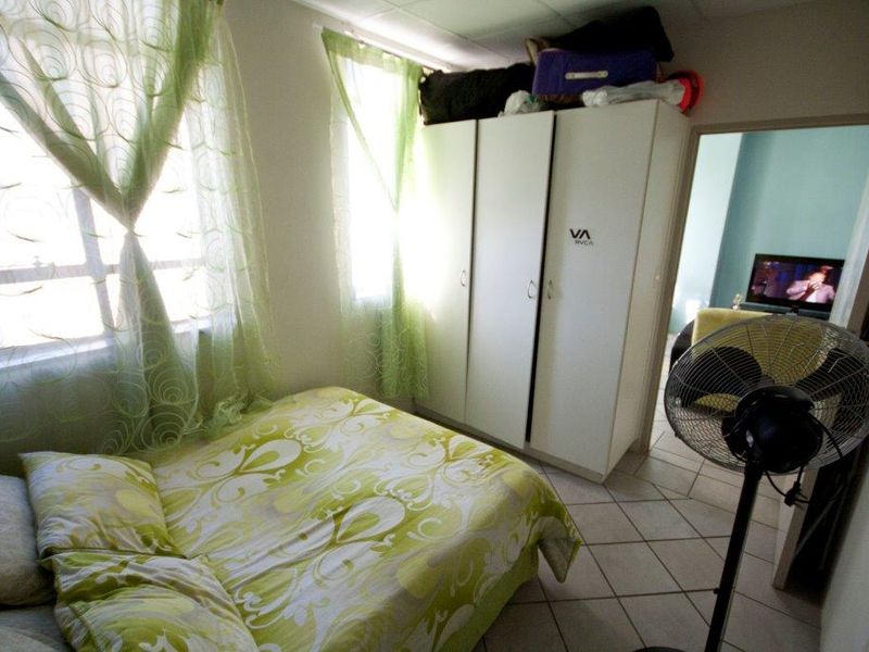 A functional bedroom featuring tiled flooring, a built-in wardrobe, and natural light from the window.