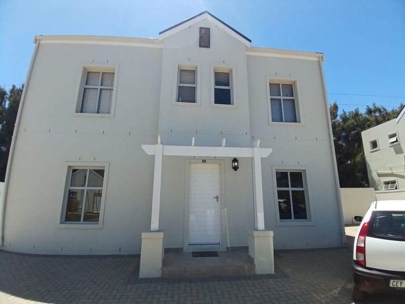 Front elevation of a two-story residential house featuring a paved driveway, a white pergola entrance, and symmetrical window placement.