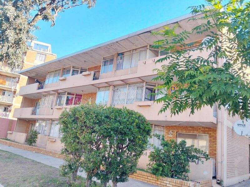 Exterior view of a multi-story apartment building featuring brick facade, private balconies, and security-fitted windows.