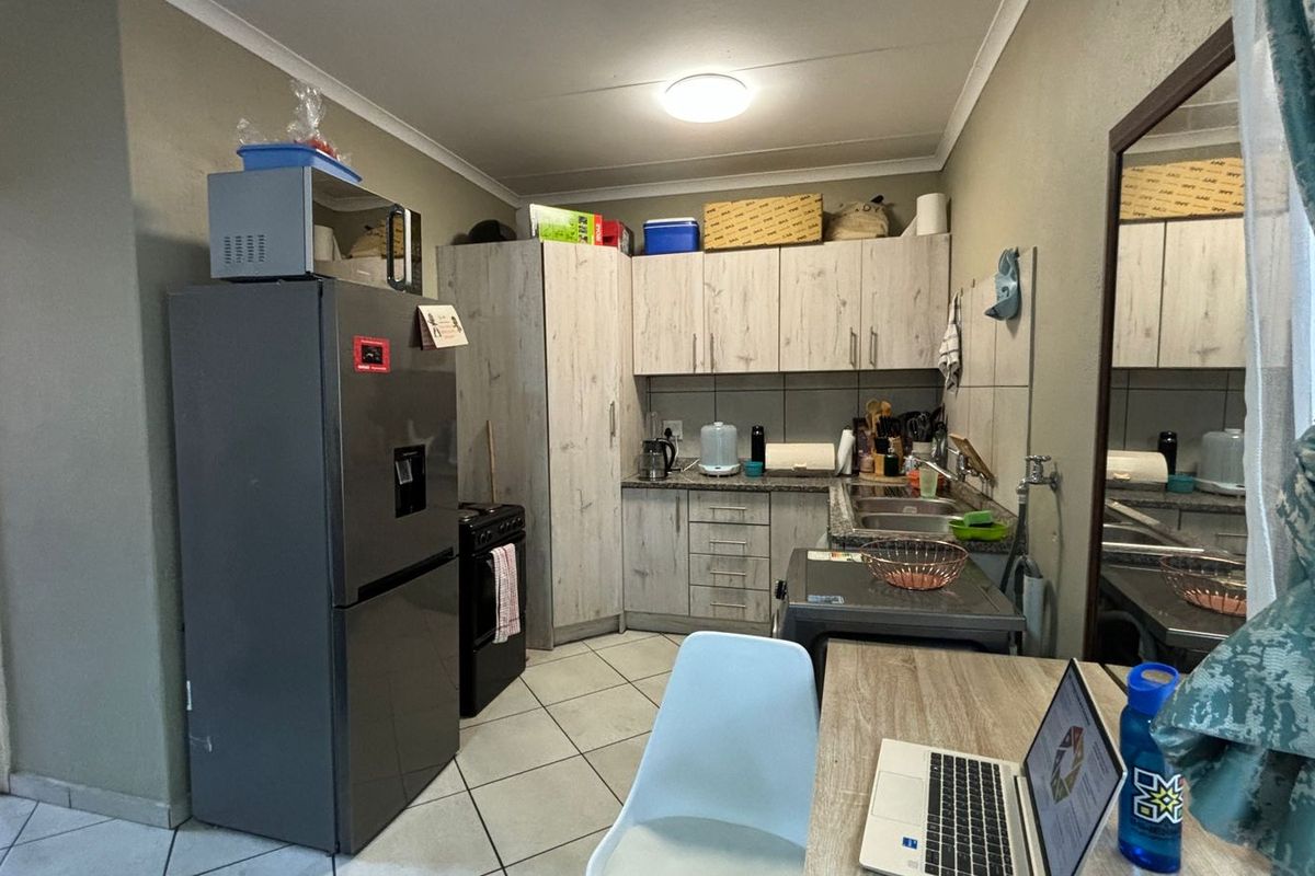 Functional kitchen featuring light wood-look cabinetry, tiled flooring, and a stainless steel sink, providing a practical workspace for daily meal preparation.