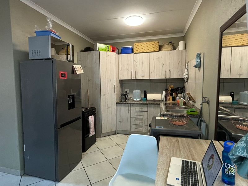 Functional kitchen featuring light wood-look cabinetry, tiled flooring, and a stainless steel sink, providing a practical workspace for daily meal preparation.