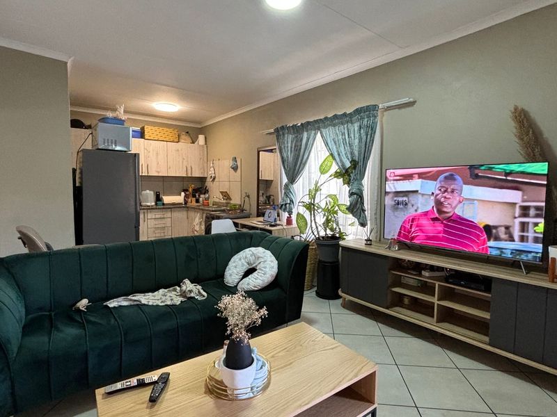Open-plan living area featuring tiled flooring and an integrated kitchen space with built-in cabinetry, providing a functional and connected layout.