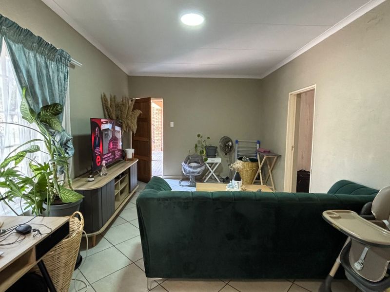 A living room featuring tiled flooring and coved ceilings, providing a functional and neutral space for relaxation.