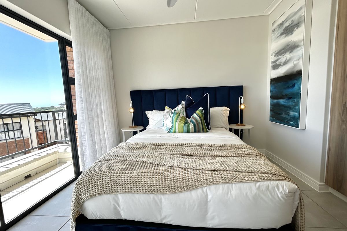 A modern, well-maintained bedroom featuring tiled flooring, a ceiling fan, and a large sliding glass door providing access to a private balcony.
