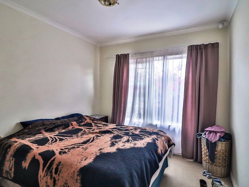 A standard bedroom featuring carpeted flooring, neutral walls, and a window with installed curtain tracks.