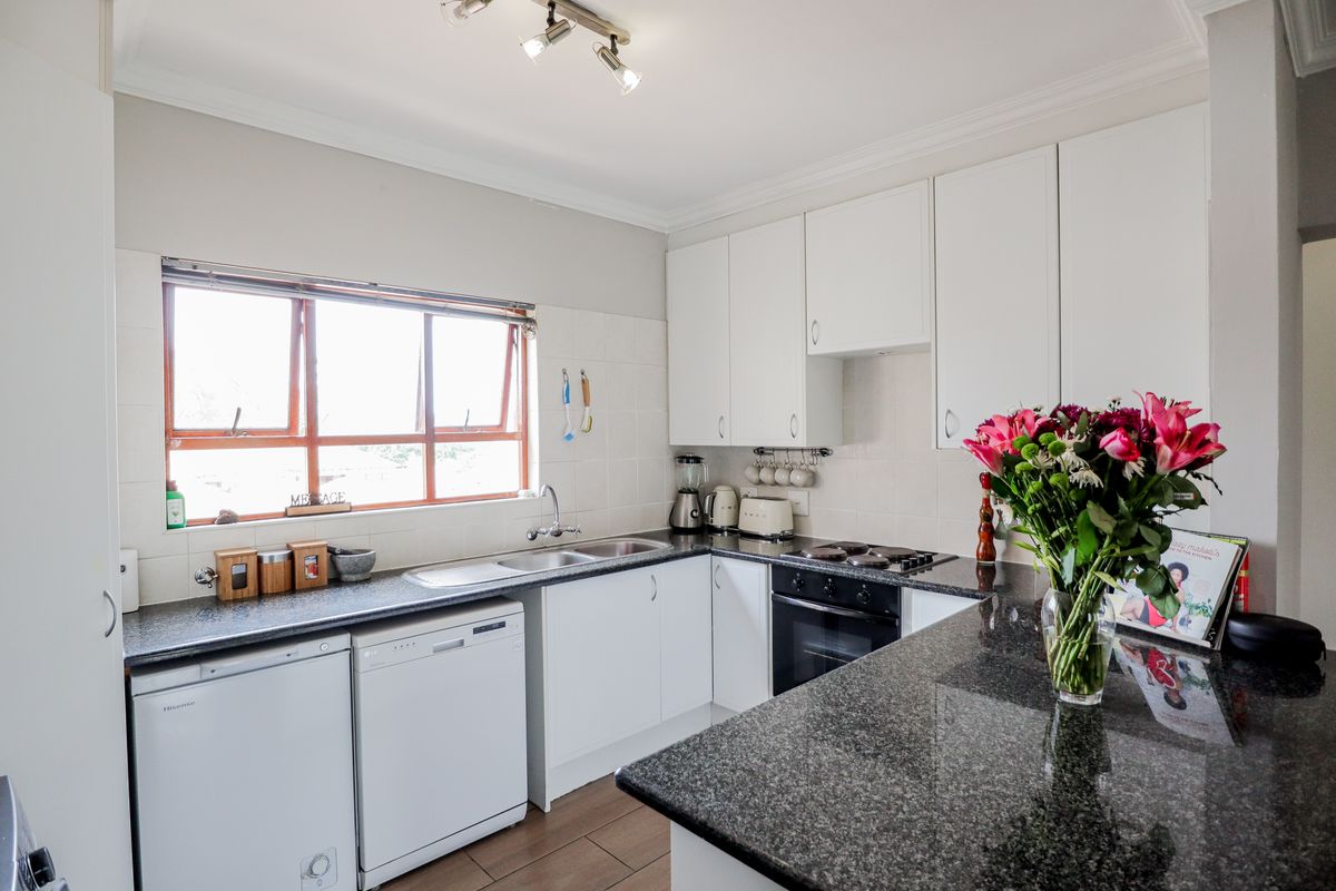 A functional kitchen featuring white cabinetry, dark granite countertops, a double sink, and a built-in oven with a hob.