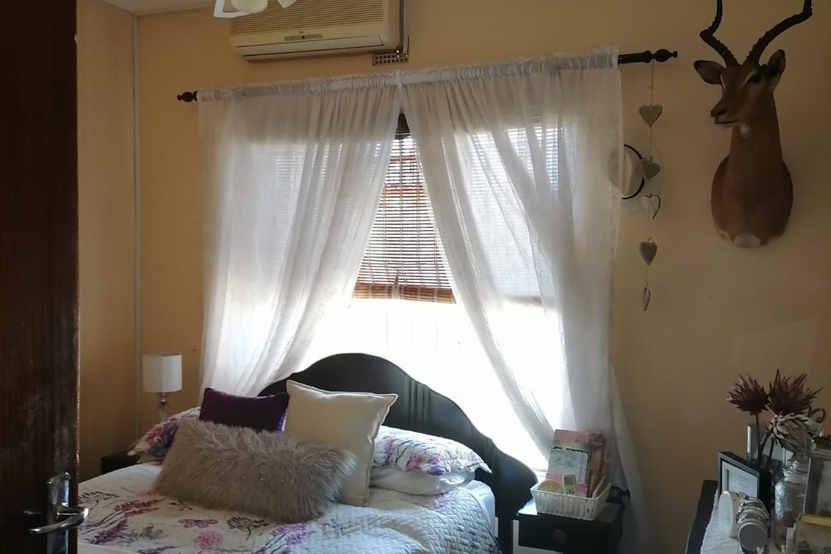 A cozy bedroom featuring a ceiling fan and a wall-mounted air conditioning unit, providing comfortable climate control.