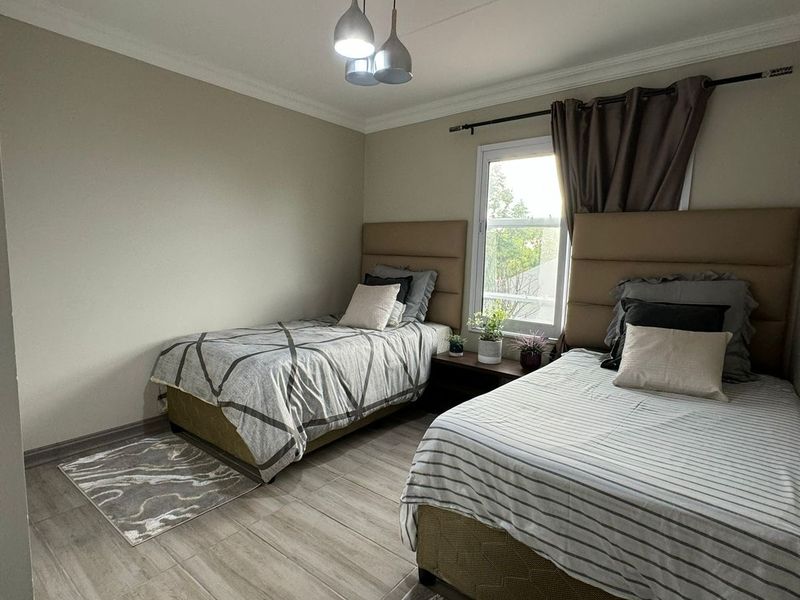A well-maintained bedroom featuring tiled flooring, cove cornicing, and a modern pendant light fixture, offering a clean and functional living space.