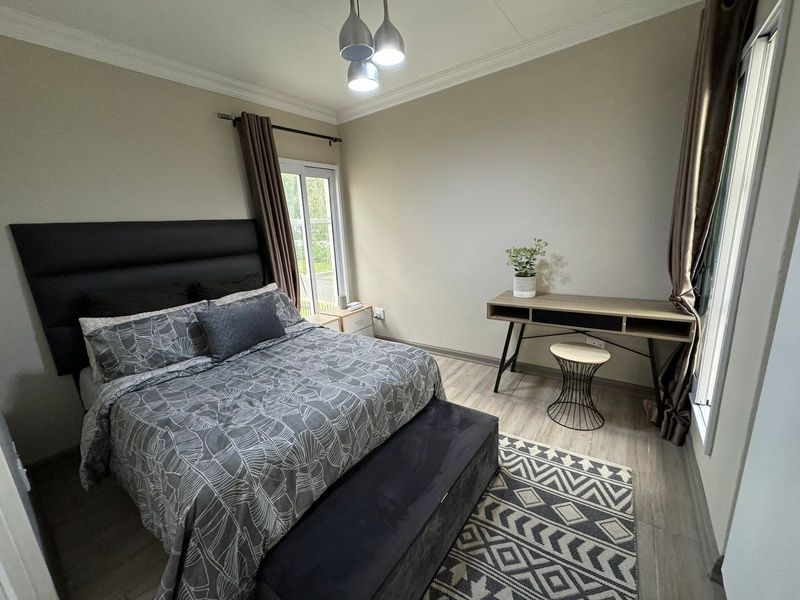 A well-maintained bedroom featuring laminate flooring, decorative cornice, and a sliding door providing natural light.