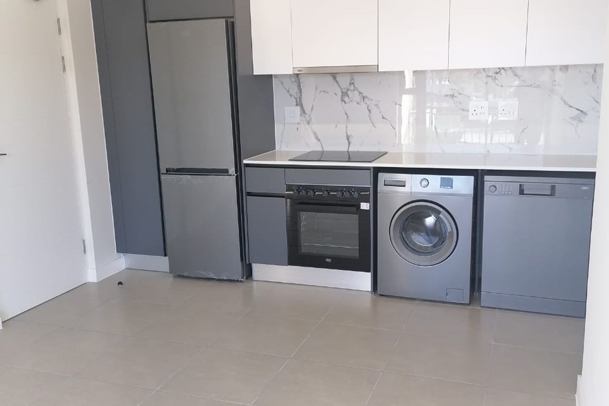 Modern kitchen featuring sleek grey and white cabinetry, marble-look splashback, integrated appliances, and neutral tiled flooring in an open-plan layout.