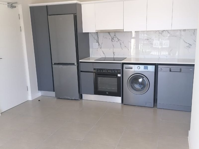 Modern kitchen featuring sleek grey and white cabinetry, marble-look splashback, integrated appliances, and neutral tiled flooring in an open-plan layout.