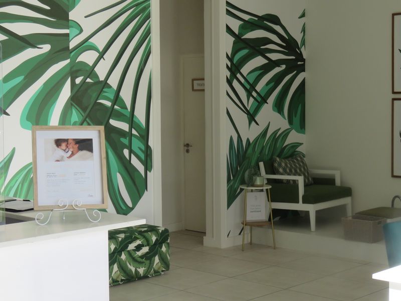 A bright and modern entry area featuring decorative botanical wallpaper, tiled flooring, and a built-in reception counter.