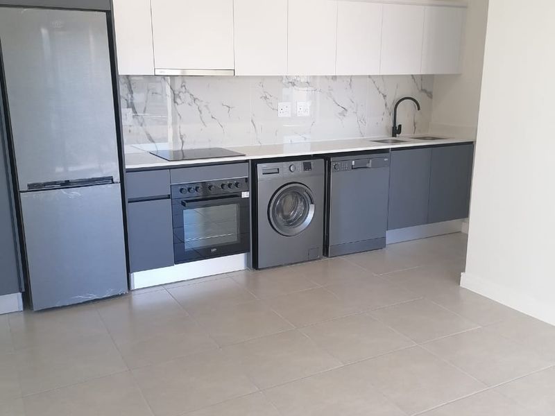 Modern kitchen featuring sleek two-tone cabinetry, marble-look splashback, integrated appliances, and neutral tiled flooring in a clean, contemporary open-plan layout.