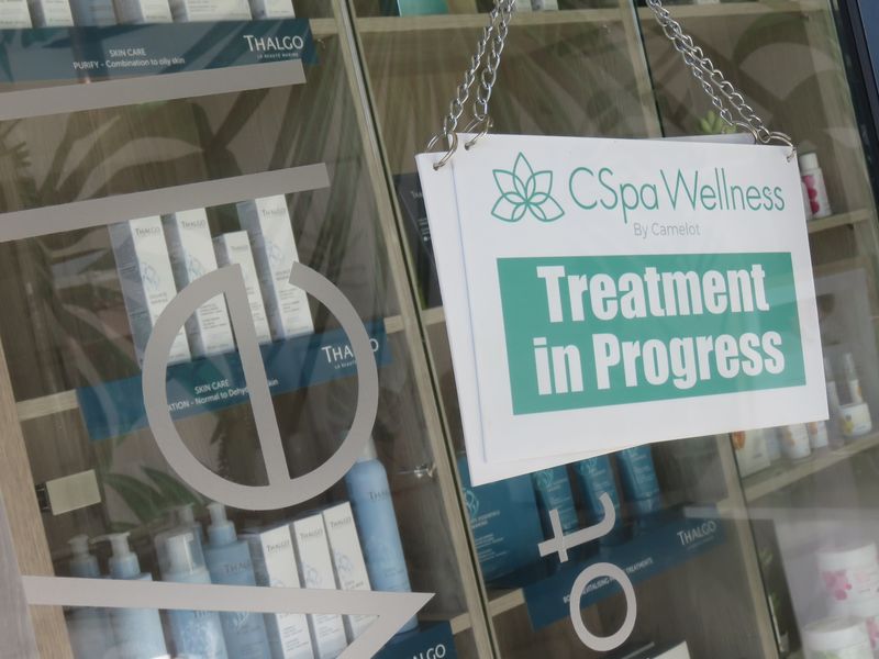 A close-up view of a retail display shelf featuring skincare products behind a glass door with a treatment in progress sign.