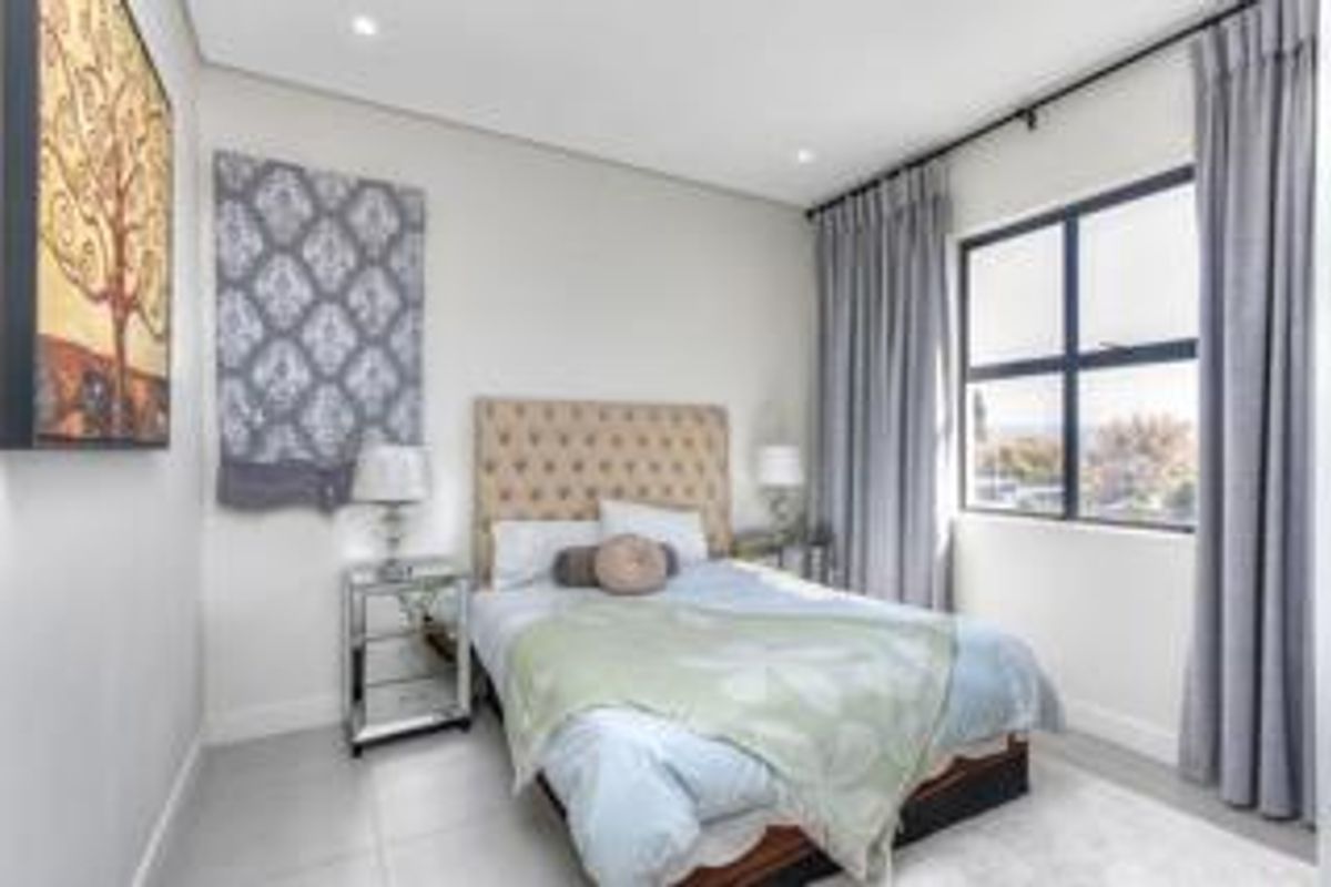 A well-maintained bedroom featuring neutral finishes, tiled flooring, recessed ceiling lighting, and a large window with curtain tracks.