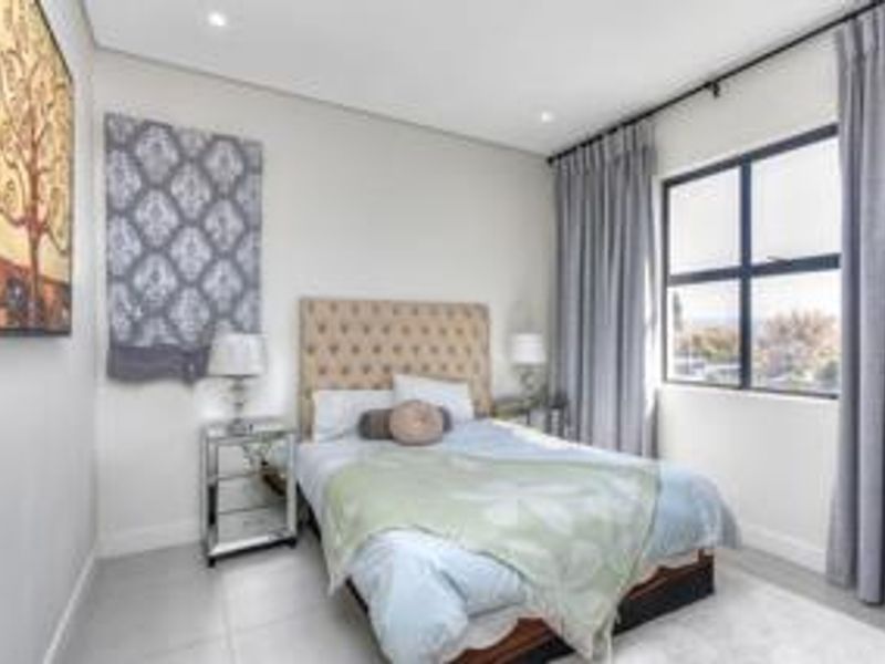 A well-maintained bedroom featuring neutral finishes, tiled flooring, recessed ceiling lighting, and a large window with curtain tracks.
