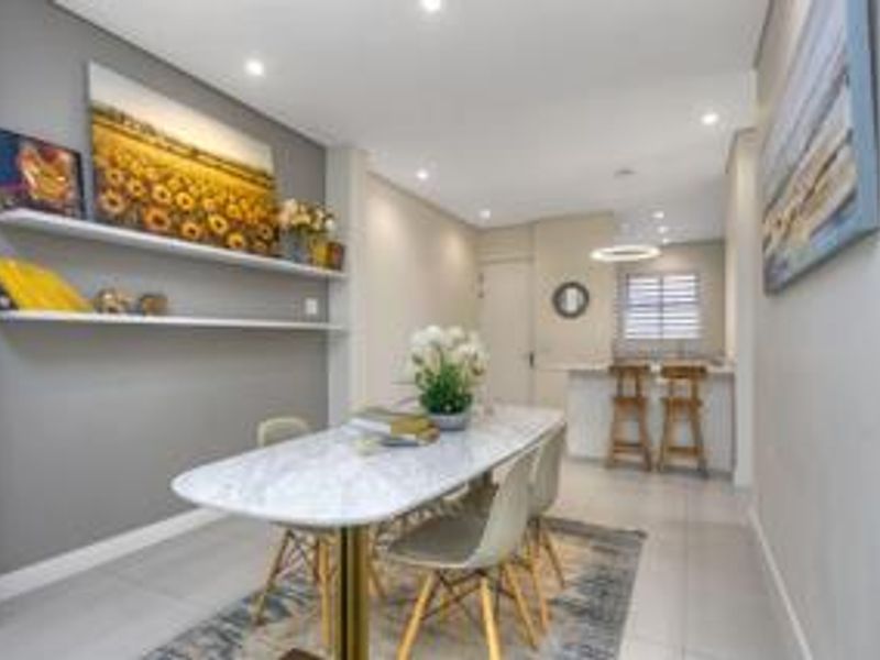 Open plan dining area featuring modern tiled flooring, recessed ceiling lighting, and a breakfast bar counter connecting to the kitchen space.
