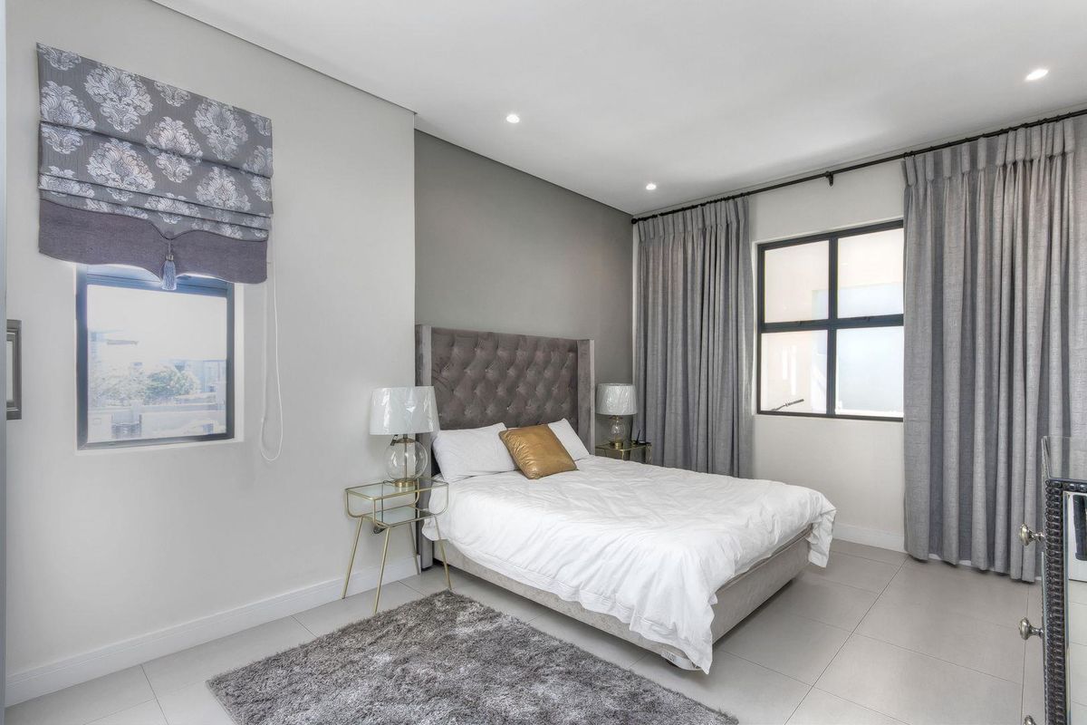 A well-maintained bedroom featuring neutral wall tones, tiled flooring, recessed ceiling lighting, and large windows with fitted curtain tracks.