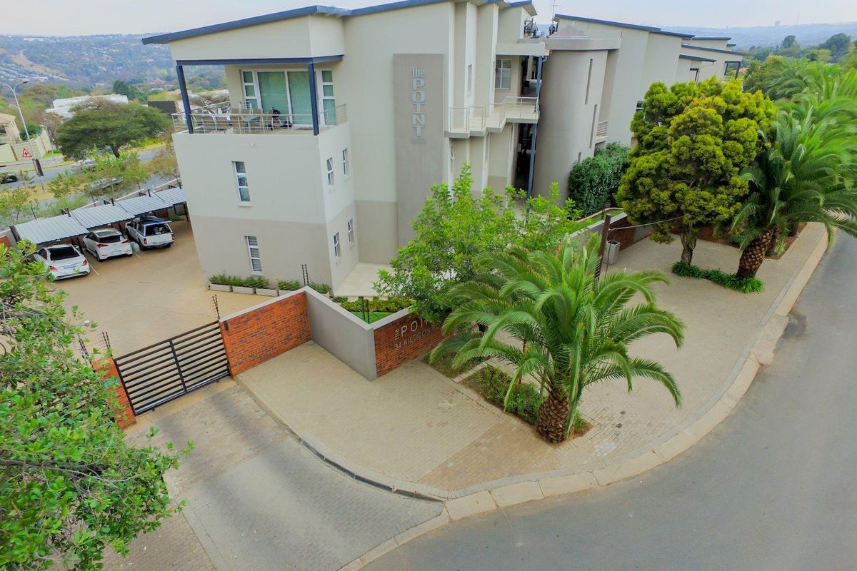 Aerial view of The Point apartment complex, featuring modern architectural design, paved driveway, secure gated entrance, and established landscaping.