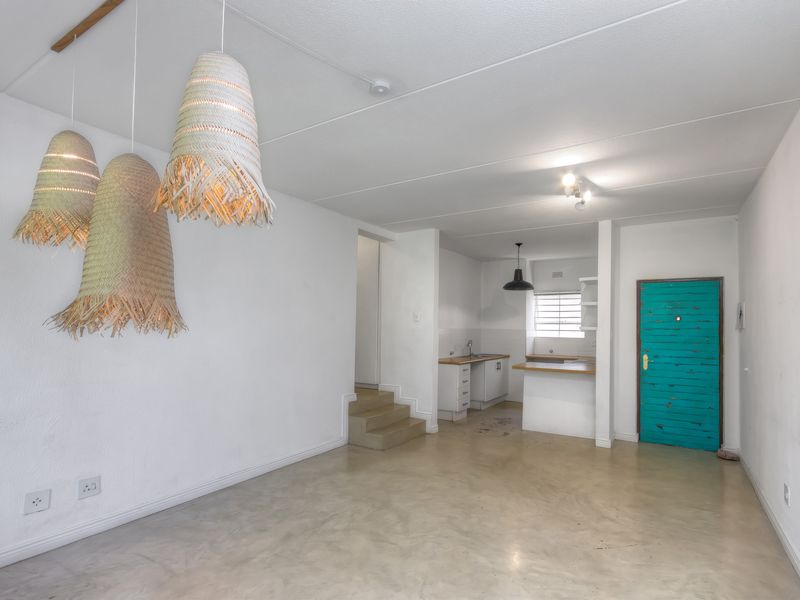 Open plan living area featuring polished concrete floors and a compact kitchen with built-in cabinetry and countertops.