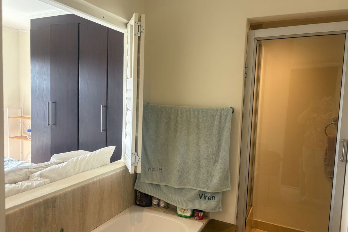 Bathroom featuring a built-in bathtub, a separate shower enclosure with a glass door, and a shutter window looking into the adjacent bedroom.