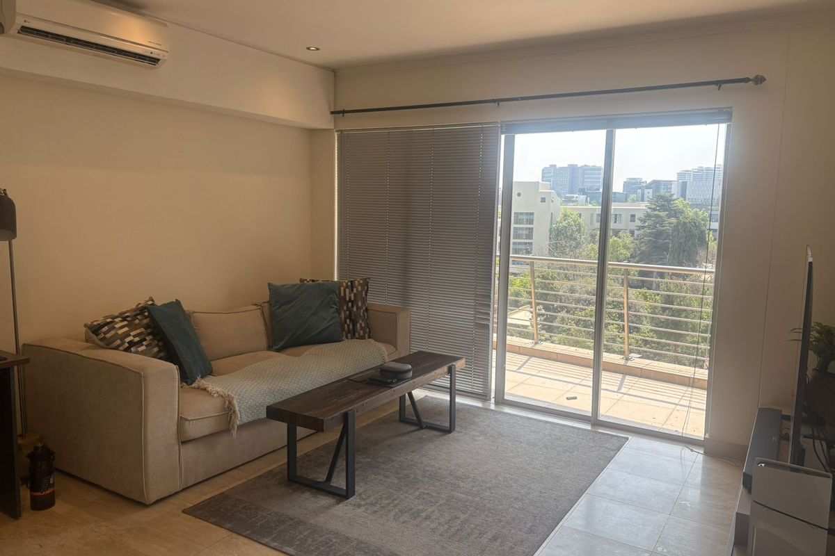 A bright living room featuring tiled floors, recessed lighting, and a split-system air conditioner, with direct access to a balcony through sliding glass doors.