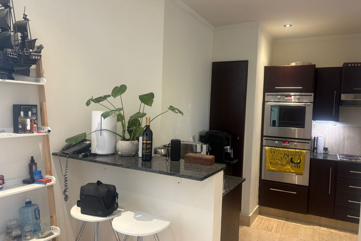 A functional kitchen featuring dark wood cabinetry, granite countertops, and integrated stainless steel appliances, including a built-in oven and microwave.