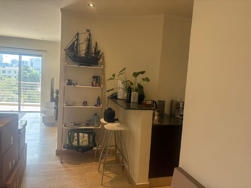 Open plan living area featuring a breakfast bar with granite countertops, tiled flooring, and access to a balcony through sliding glass doors.