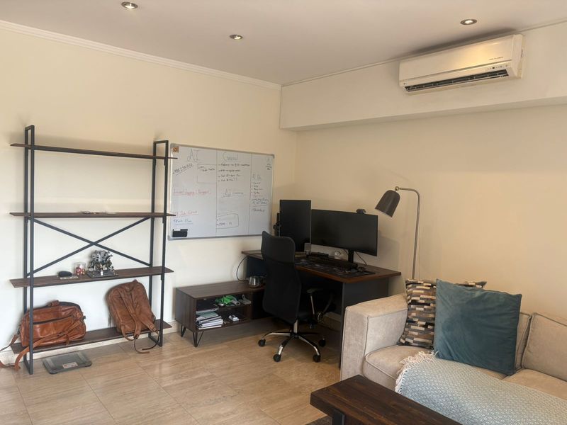 A functional home office space featuring tiled flooring, recessed downlighting, and a wall-mounted split-system air conditioning unit.