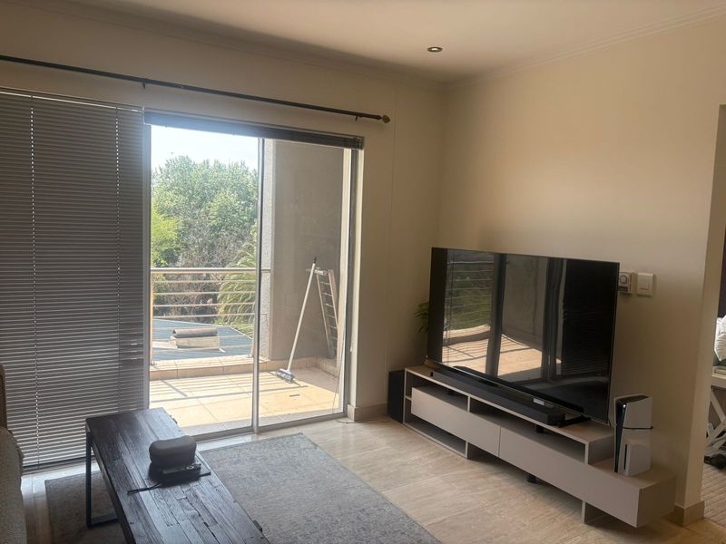 A bright living room featuring tiled flooring, recessed lighting, and a large sliding glass door providing direct access to an outdoor balcony area.