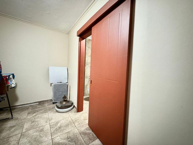 A functional hallway area featuring tiled flooring and a prominent sliding door leading to an adjacent room.