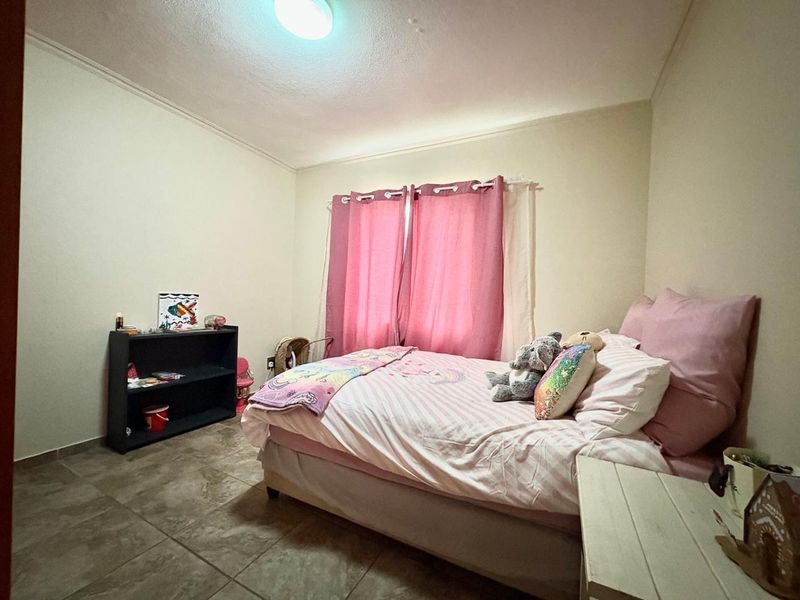 A bedroom featuring tiled flooring and a central ceiling light fixture, providing a functional space with neutral wall finishes.