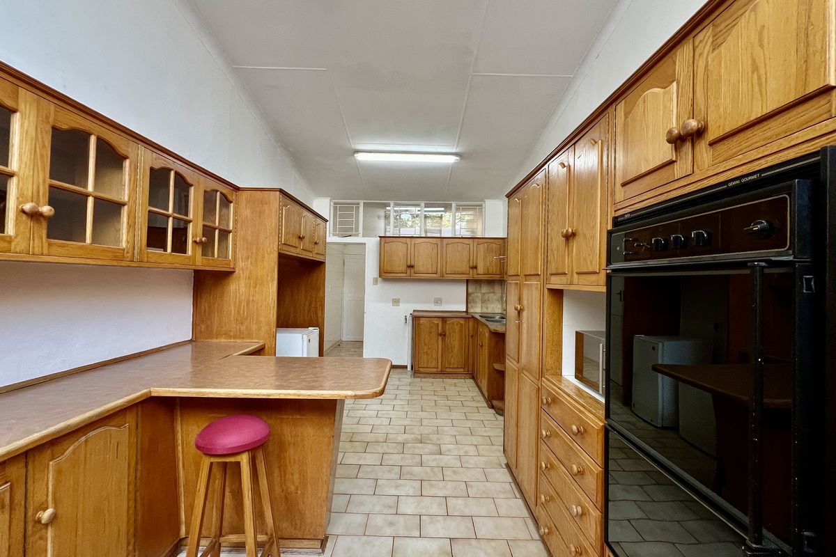 A functional kitchen featuring extensive built-in wooden cabinetry, laminate countertops, and a built-in double oven, finished with ceramic tile flooring.
