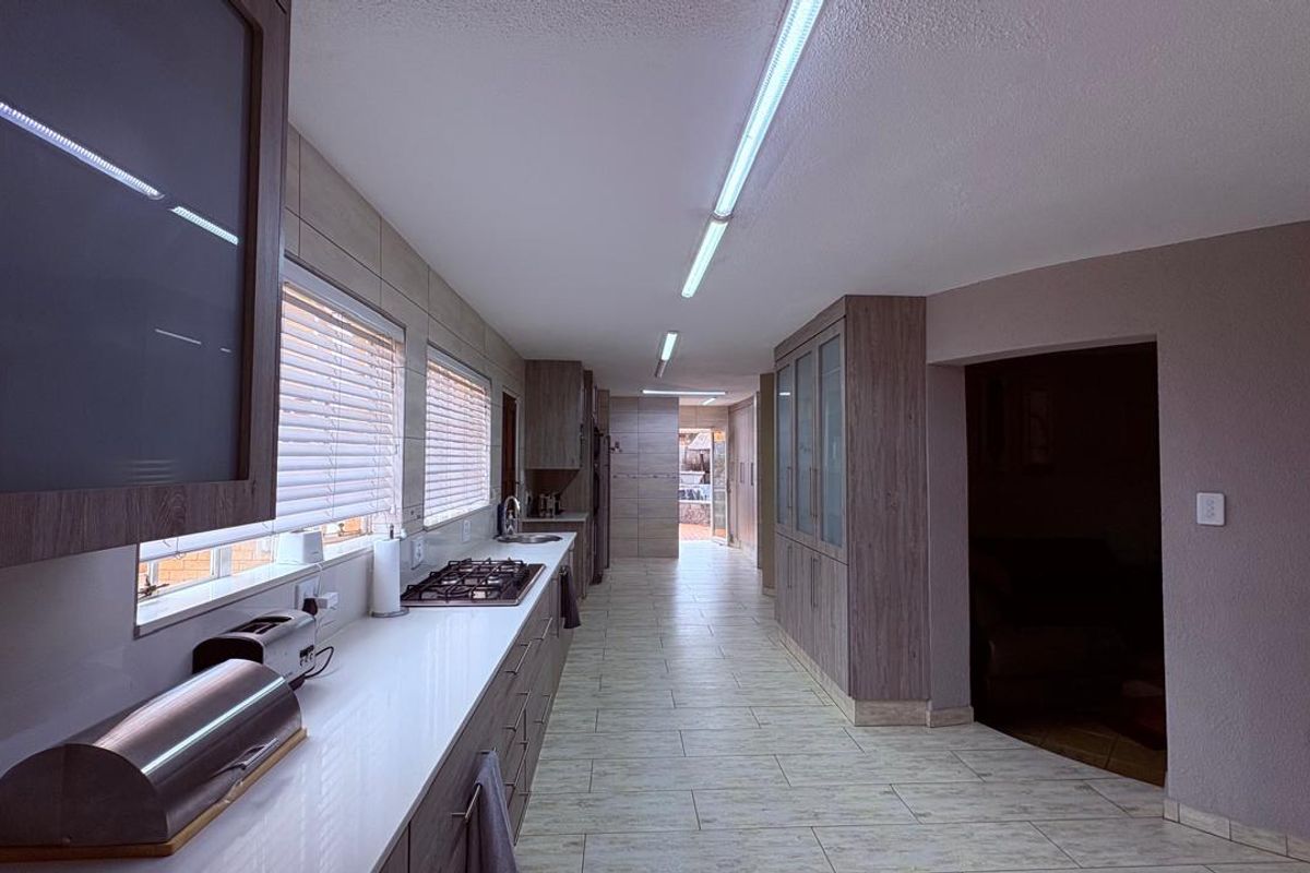 Modern galley-style kitchen featuring extensive built-in cabinetry, a gas hob, and tiled flooring with ample counter space.