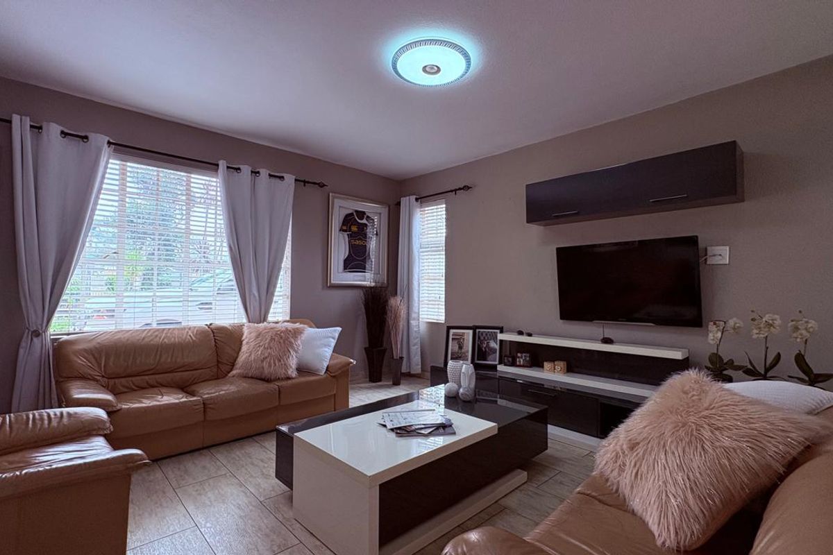 A comfortable living room featuring tiled flooring, neutral wall tones, and built-in wall-mounted cabinetry for media storage.