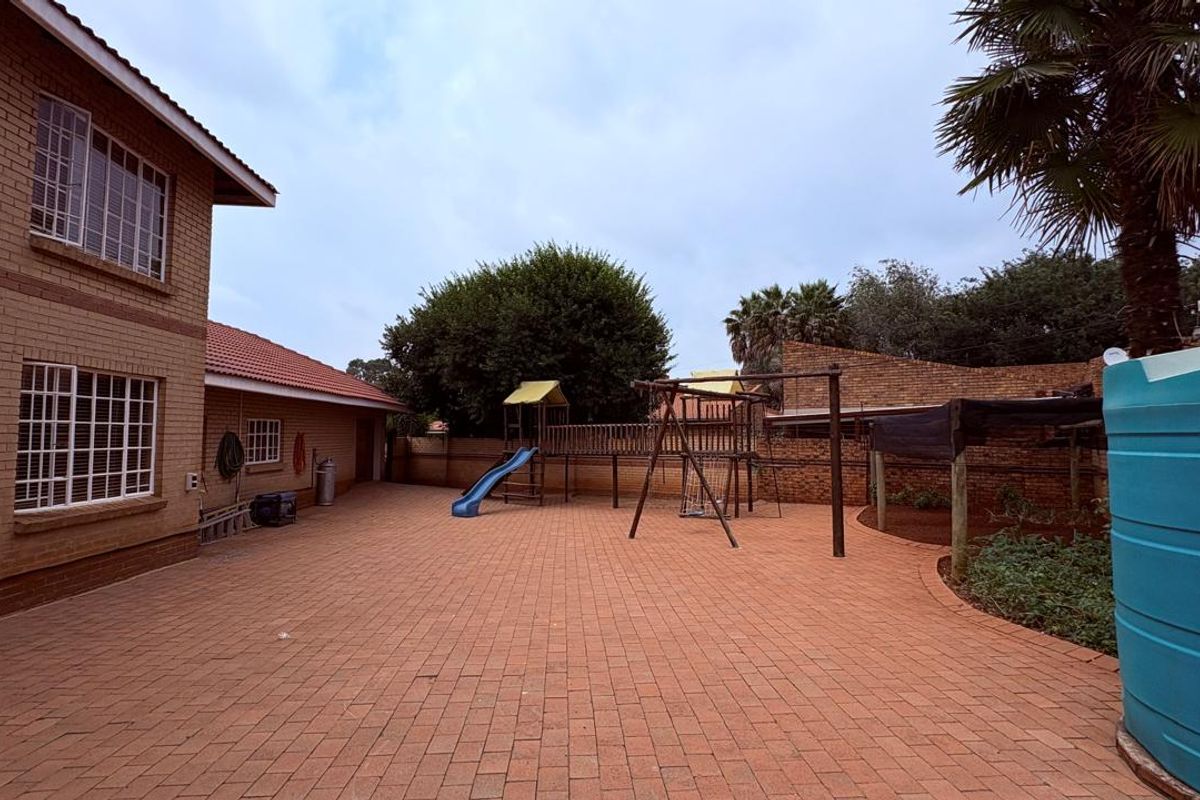 Spacious rear courtyard featuring extensive brick paving, face brick exterior walls, and a large water storage tank, providing a functional outdoor area.