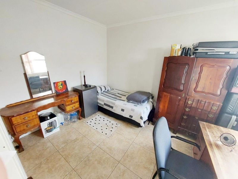 A functional bedroom featuring tiled flooring and neutral wall finishes, providing a versatile space for rest or study.