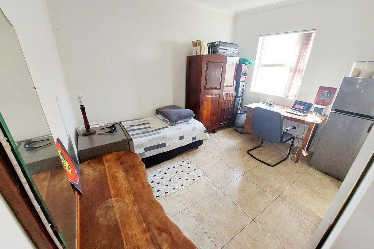 A functional bedroom featuring tiled flooring and a window, providing a practical living space with neutral wall finishes.