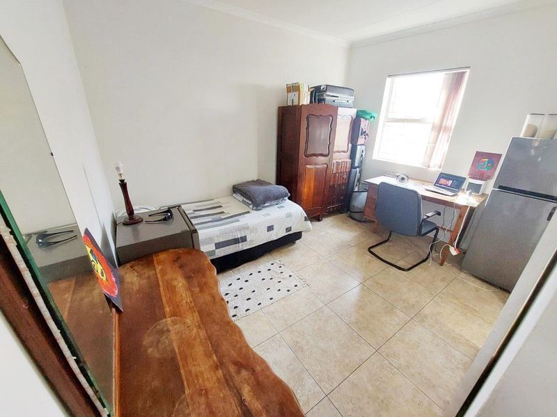 A functional bedroom featuring tiled flooring and a window, providing a practical living space with neutral wall finishes.