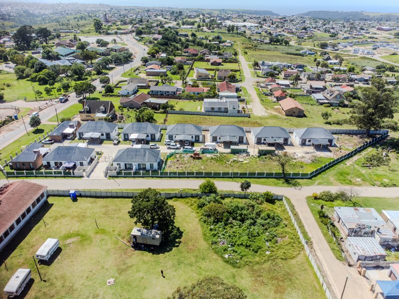 An aerial view of a residential complex featuring multiple detached houses with paved driveways and perimeter fencing in a suburban setting.