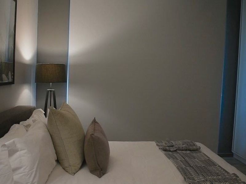 A modern bedroom featuring a built-in wardrobe and ambient recessed wall lighting, creating a comfortable and contemporary sleeping space.