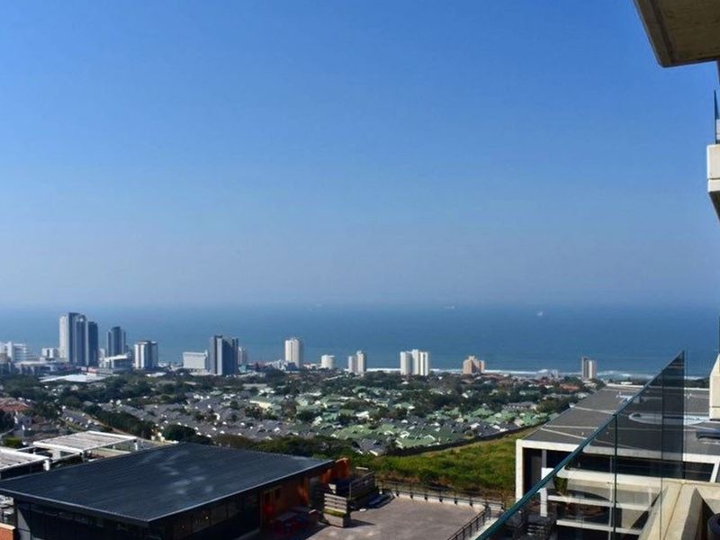 Elevated panoramic view overlooking the coastal city skyline, residential suburbs, and the ocean from a private balcony.