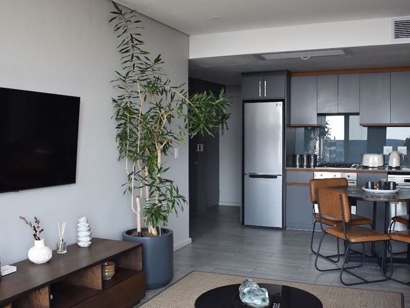 Modern open-plan living area featuring a sleek kitchen with contemporary cabinetry, tiled flooring, and integrated ducted air conditioning.