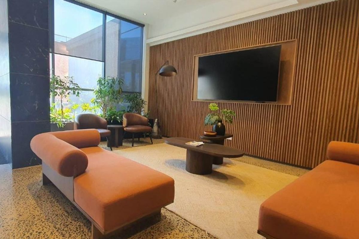 Modern living area featuring stylish timber slat wall paneling, polished concrete floors, and expansive floor-to-ceiling windows providing ample natural light.
