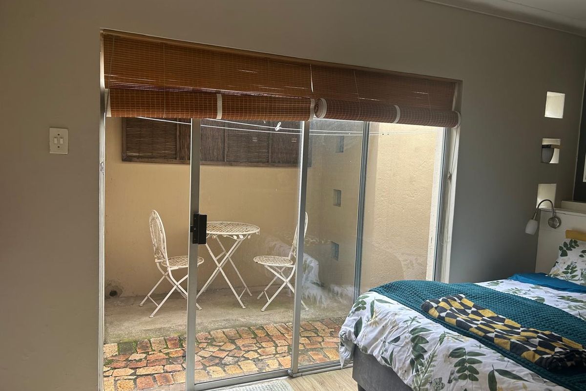 Bedroom featuring laminate flooring and a sliding glass door providing direct access to a private paved patio area.