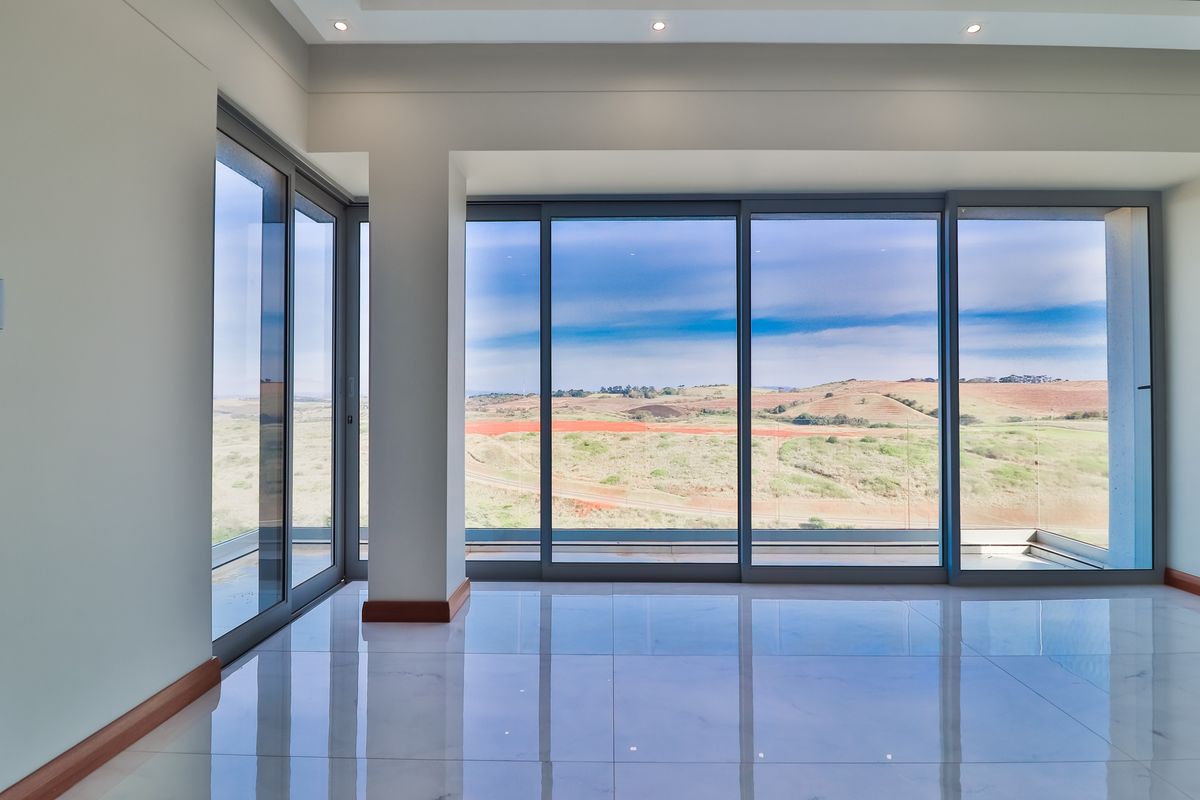 A bright, modern living area featuring expansive floor-to-ceiling sliding glass doors that offer panoramic views of the surrounding landscape.