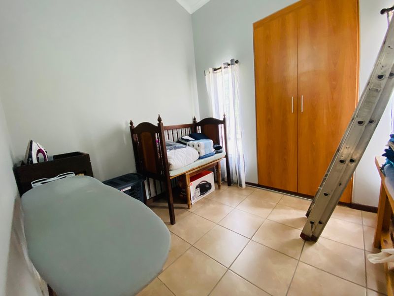 A bedroom featuring tiled flooring and a built-in wooden wardrobe, offering functional storage space within the apartment.